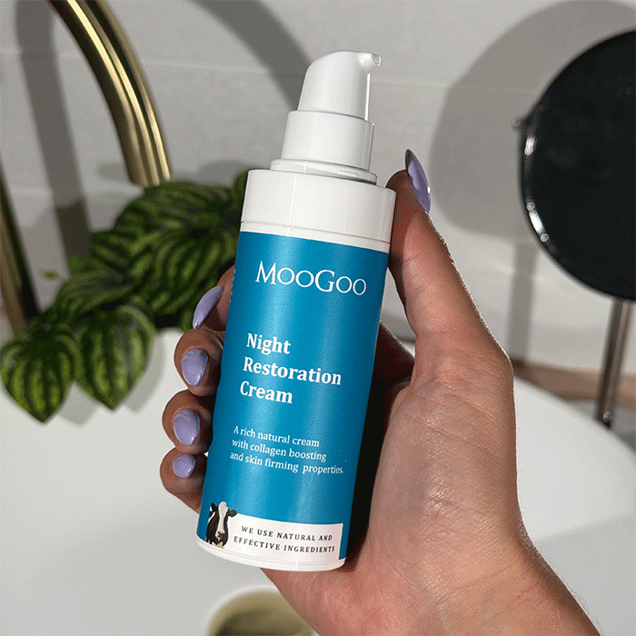 Hand holding MooGoo Night Restoration Cream pump bottle in bathroom, natural night moisturiser with collagen boosting and hydrating ingredients
