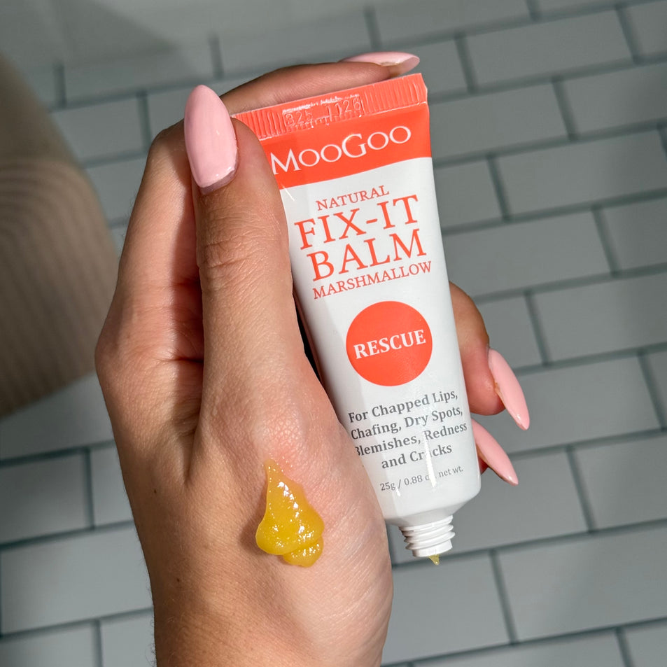 hand with swatch spread on it, holding MooGoo Natural Fix It Balm, Petroleum free, for chapped lips, dry spots, blemishes. redness and cracks