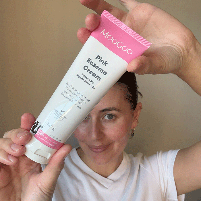 Person holding a tube of MooGoo Pink Eczema Cream in front of their face.
